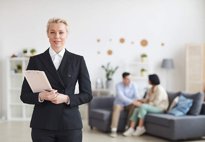 Pracownik biurowy z tablicą, w tle para na kanapie